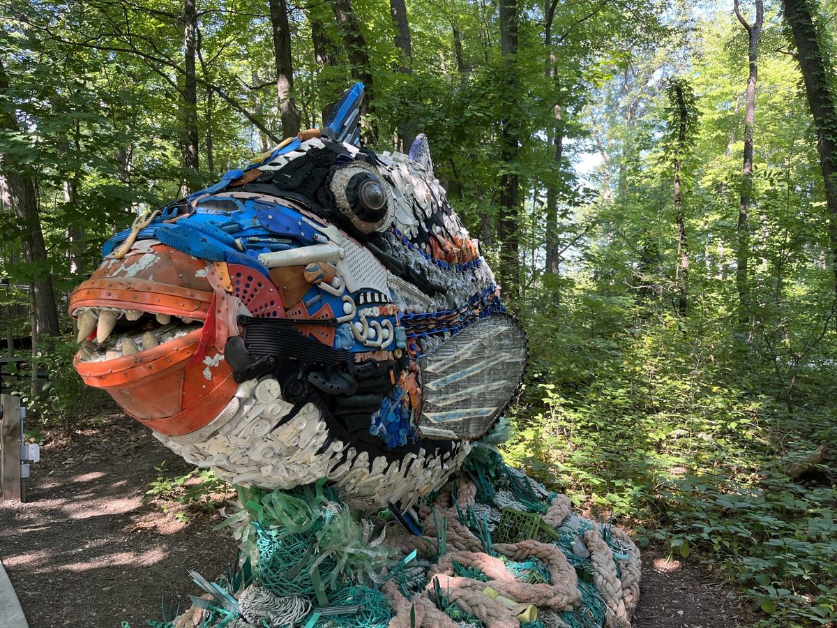 A photo of a sculpture of a fish made from various bits of colorful trash, from discarded netting to garden tools.